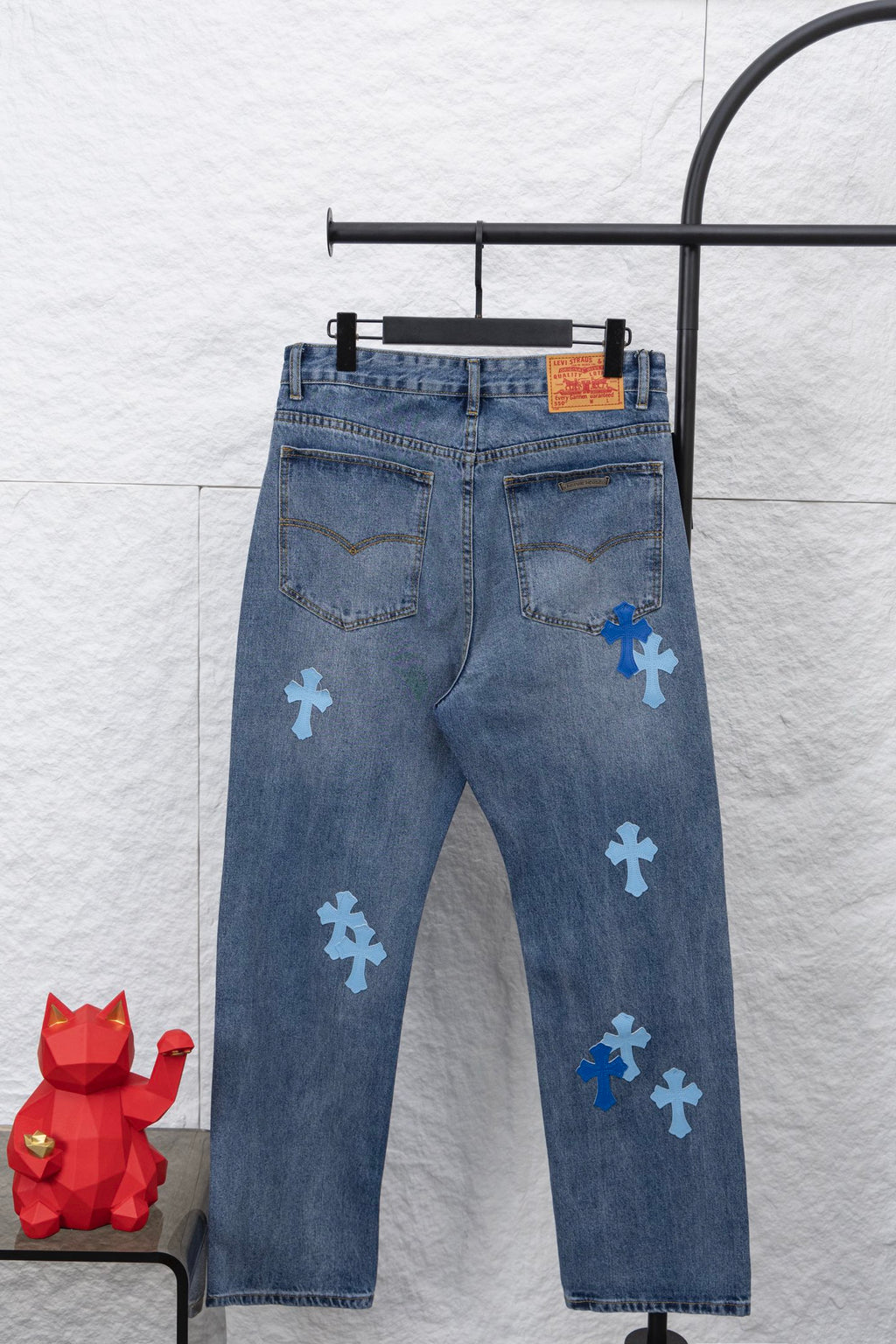 Light blue denim pants with blue cross patches and a visible back yoke