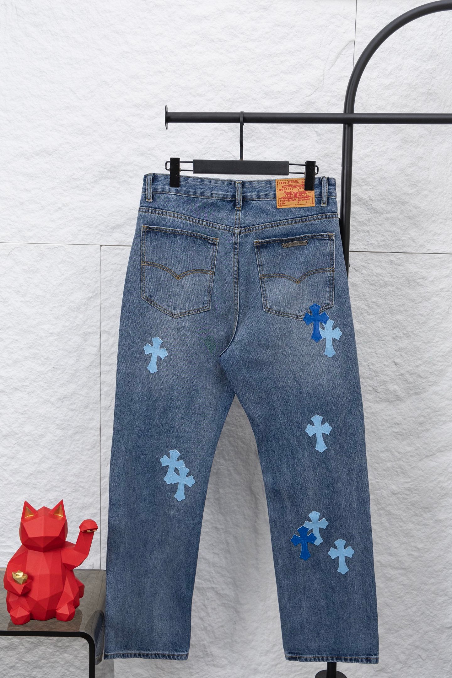Light blue denim pants with blue cross patches and a visible back yoke