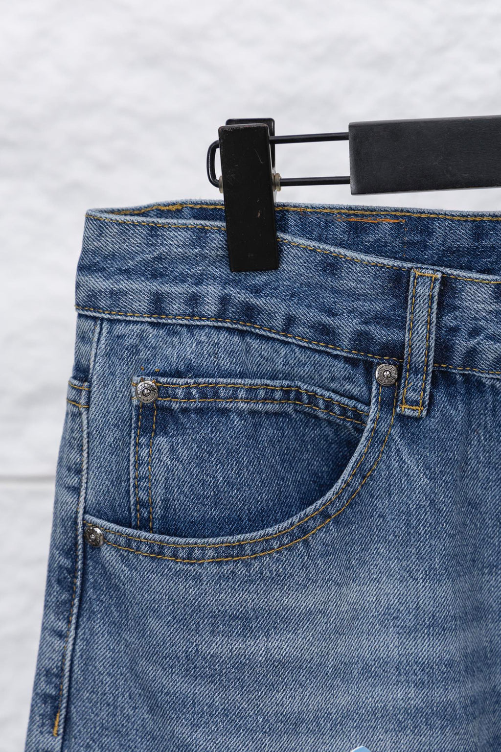 Light blue denim pants with back pocket, stitching, and small coin pocket
