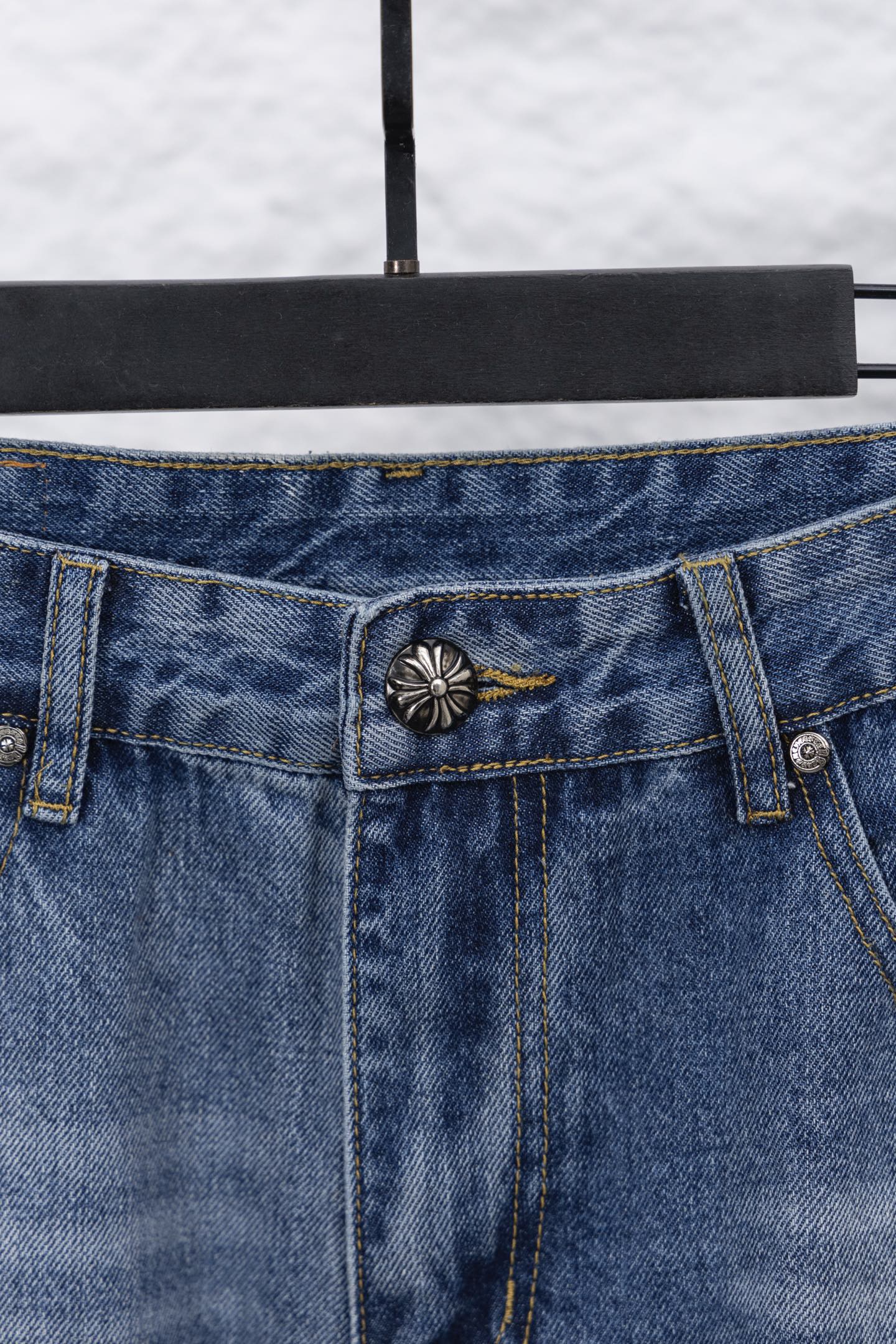 Light blue denim waistband with center button and decorative patch on pocket