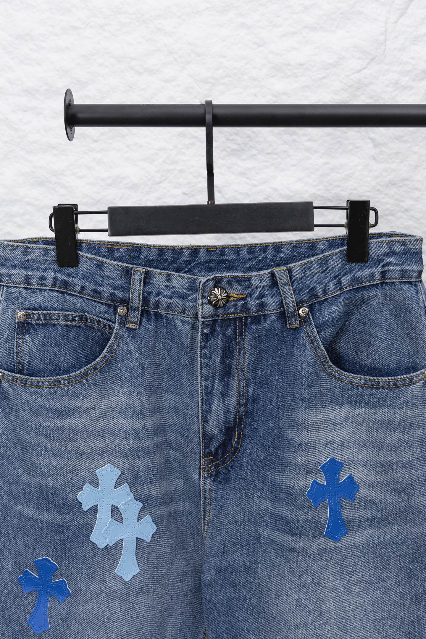 Light blue denim pants with front pockets and scattered blue cross patches