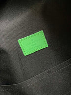 Louis Vuitton bag with neon-green label patch on dark fabric interior