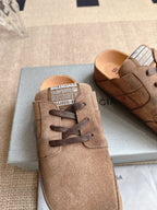 Brown suede lace-up sandals with printed logo label on tongue, close-up