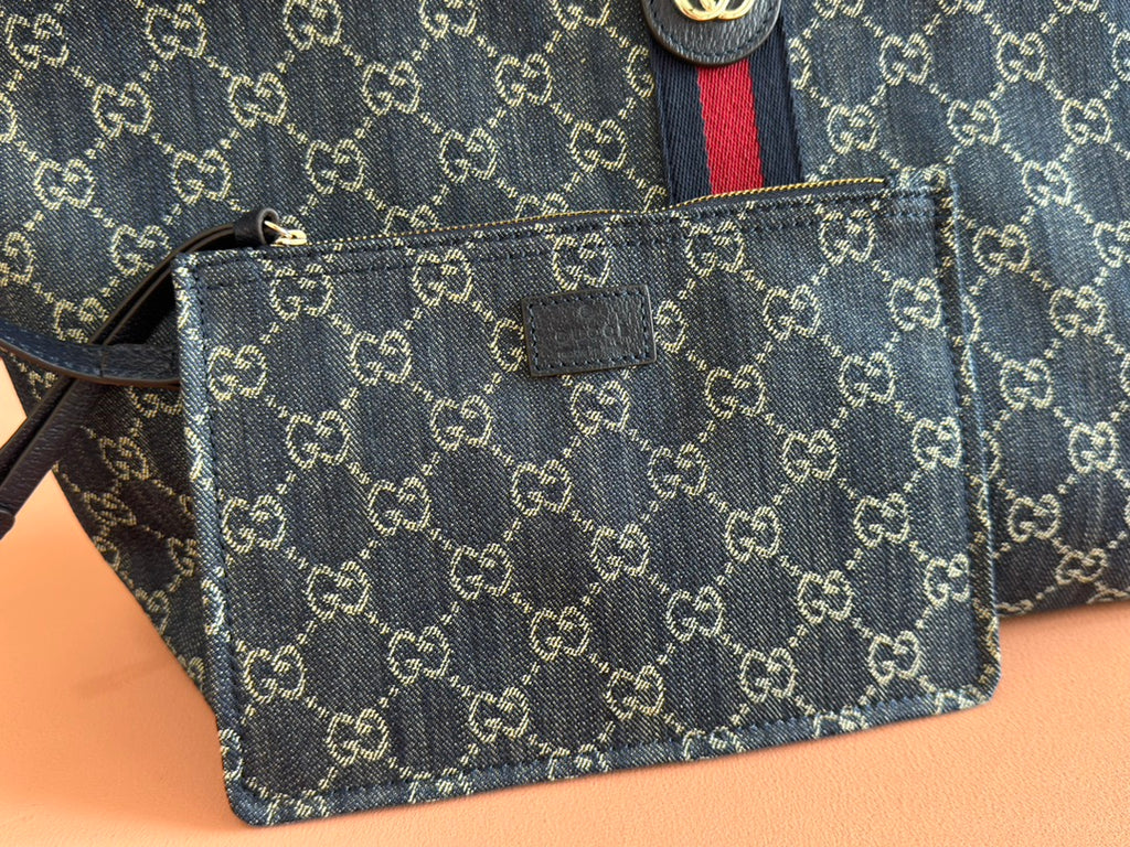 Small monogram pouch accessory with zipper and leather strap attached to the tote bag