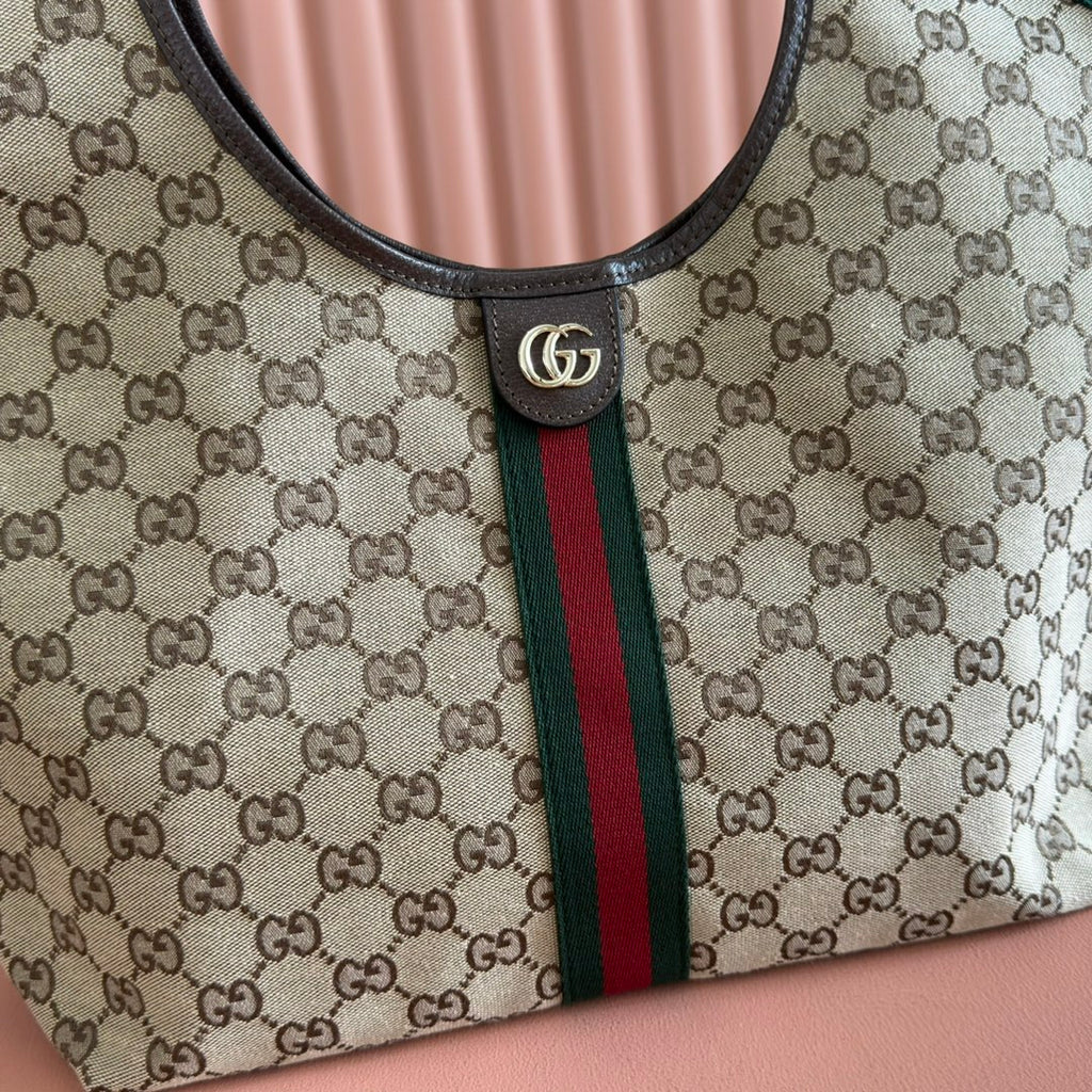 Gucci bag detail: round GG emblem snap, black leather collar, green/red web stripe