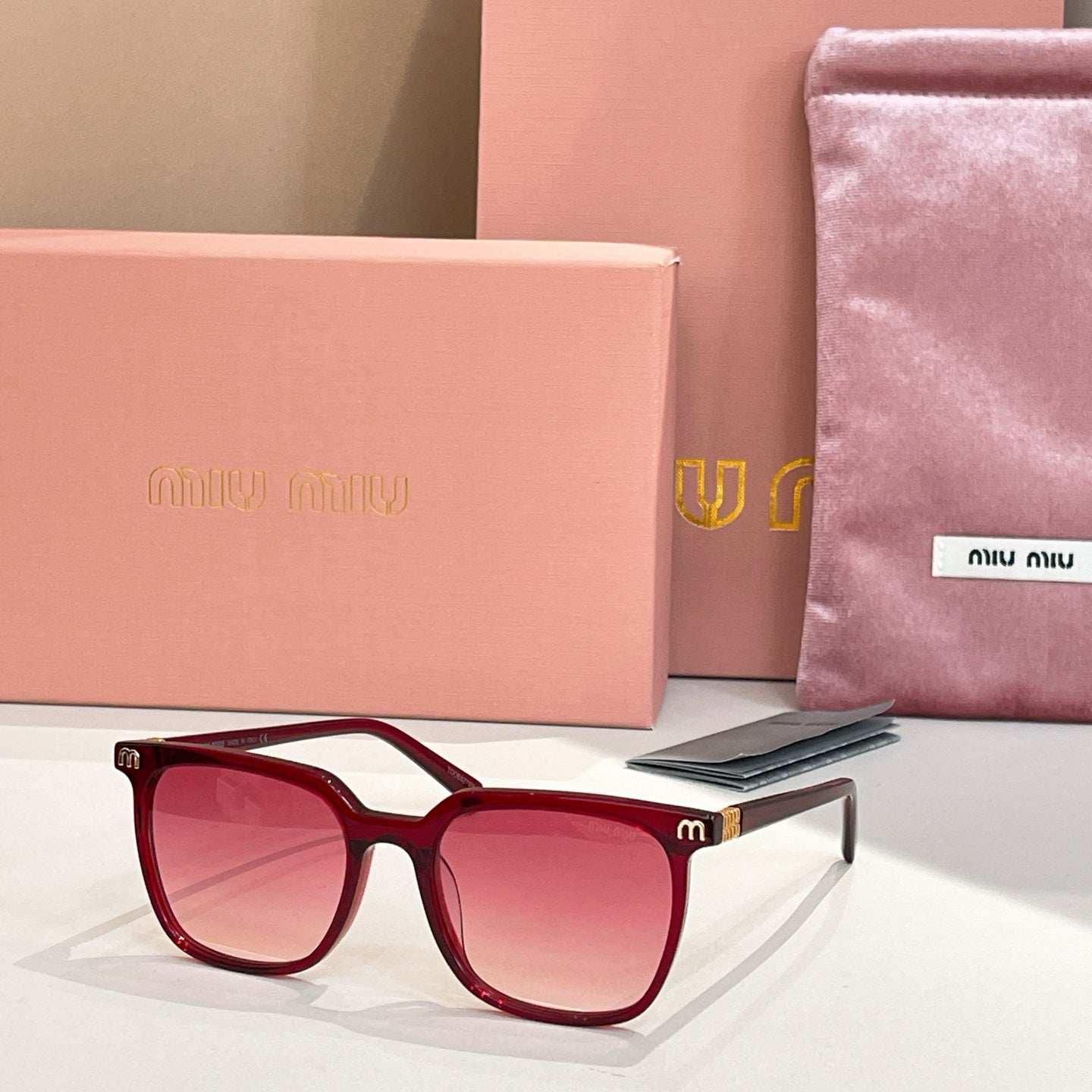 Sunglasses with burgundy square frames and pink tinted lenses, metal accents on temples