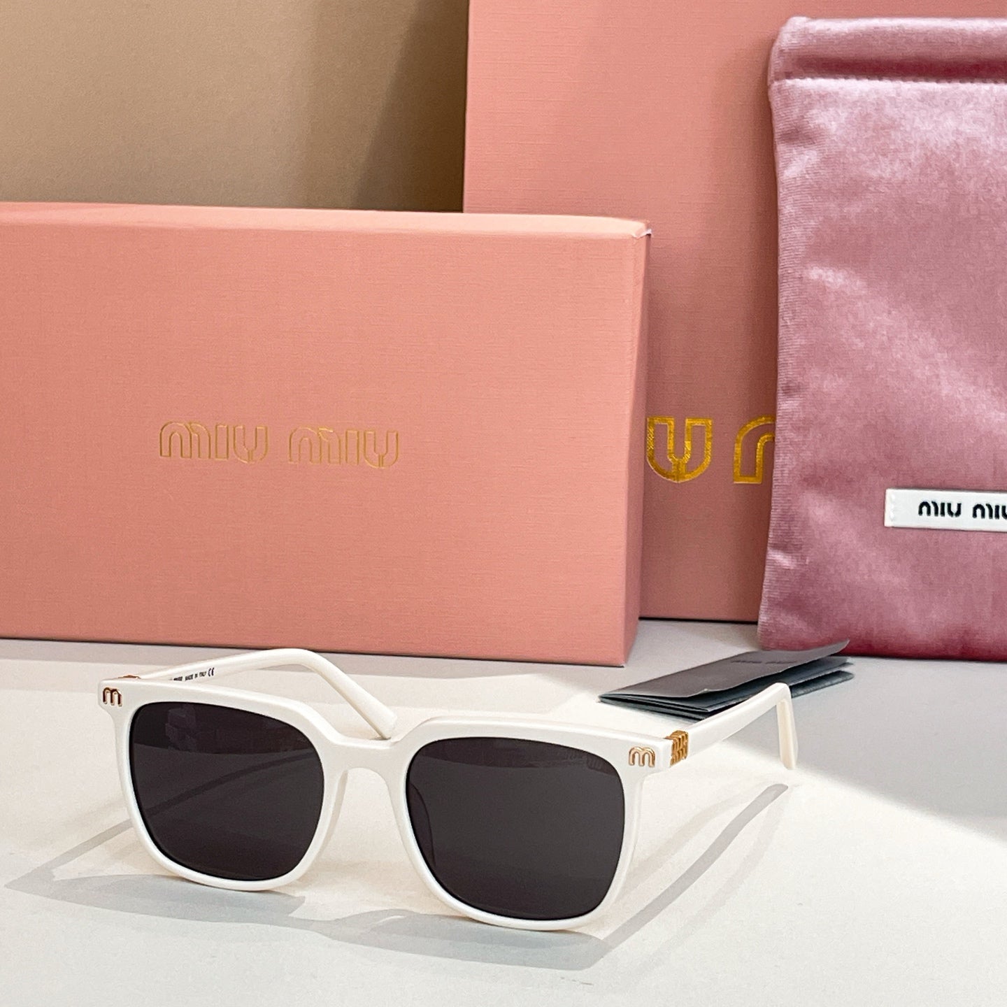 Sunglasses with white square frames and dark tinted lenses, metal accents on temples