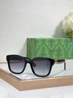 Gucci sunglasses with black frame and dark lenses, gold-toned temple accents.
