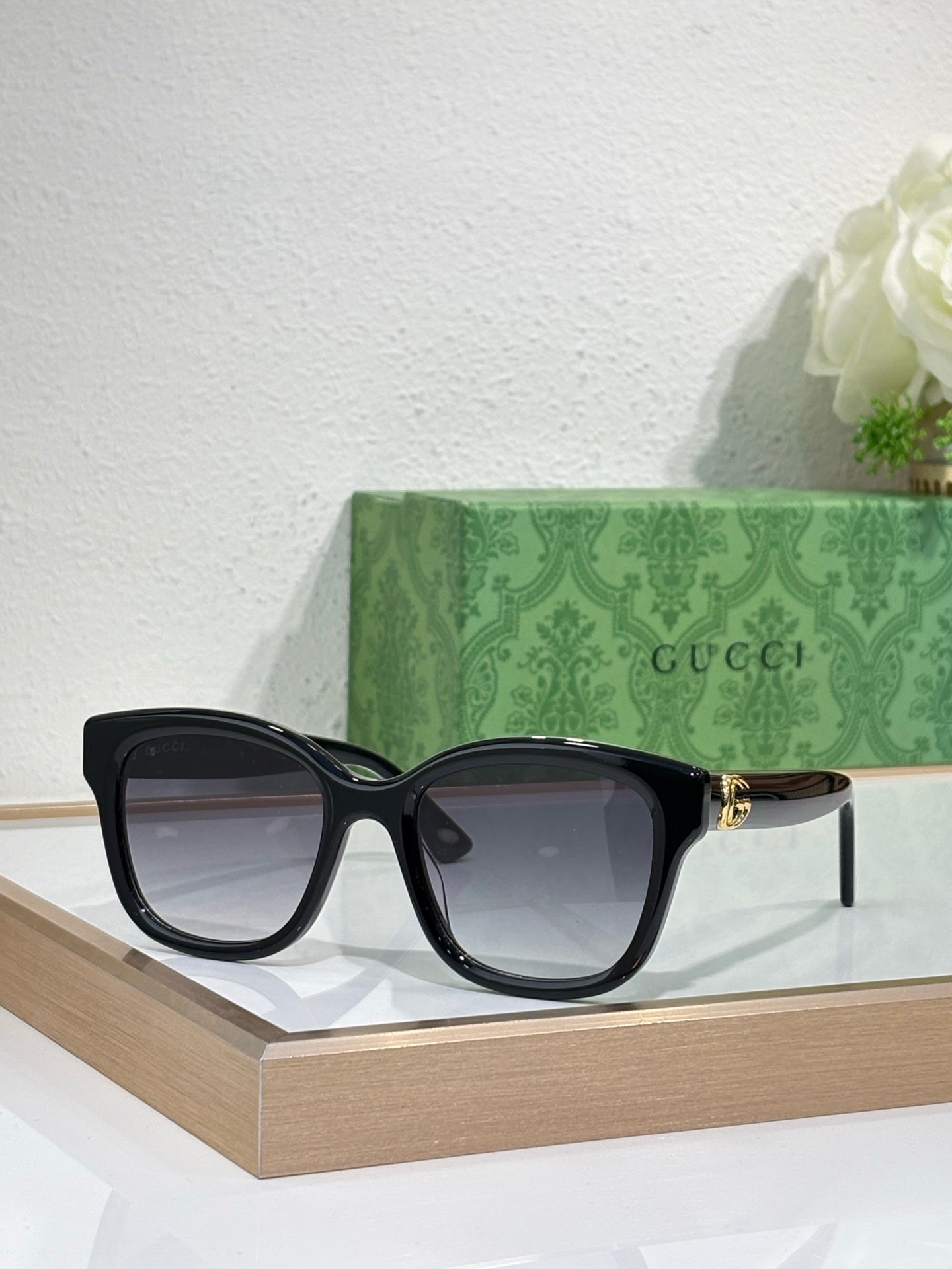Gucci sunglasses with black frame and dark lenses, gold-toned temple accents.