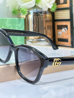 Gucci sunglasses side view with black frame, gold logo on temple, dark lens.