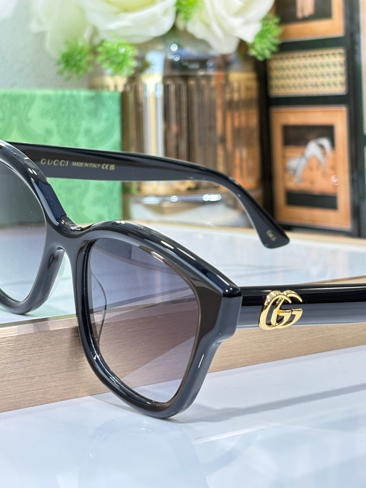 Gucci sunglasses side view with black frame, gold logo on temple, dark lens.