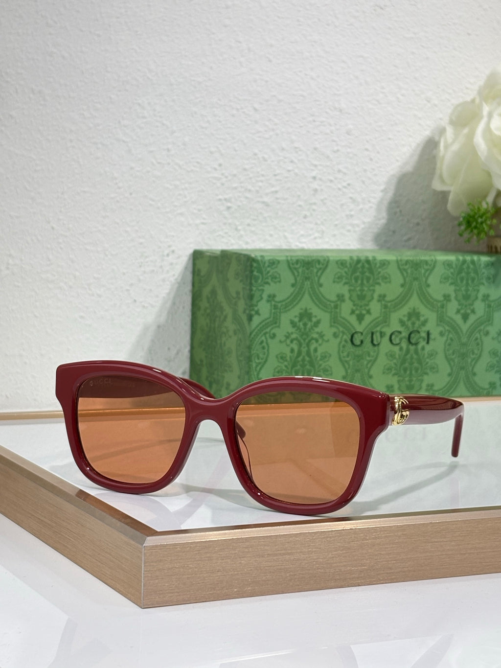 Gucci sunglasses with red frame and tinted lenses, gold-toned temple accents.