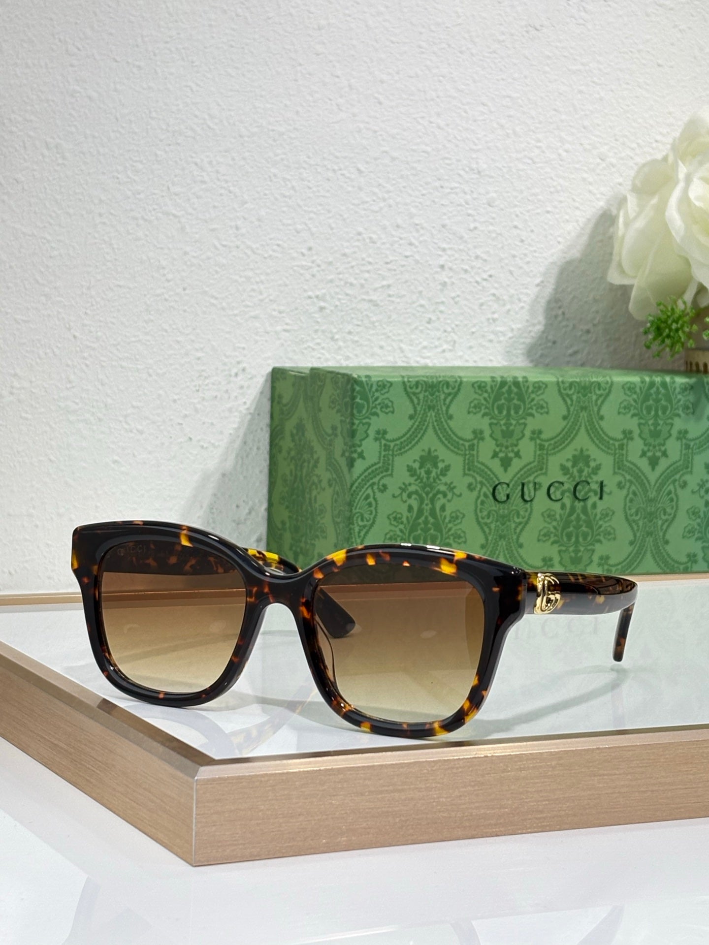 Gucci sunglasses with tortoiseshell frame and tinted lenses, gold-toned temple accents.