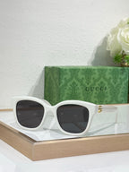 Gucci sunglasses with white frame and dark lenses, gold-toned temple accents.