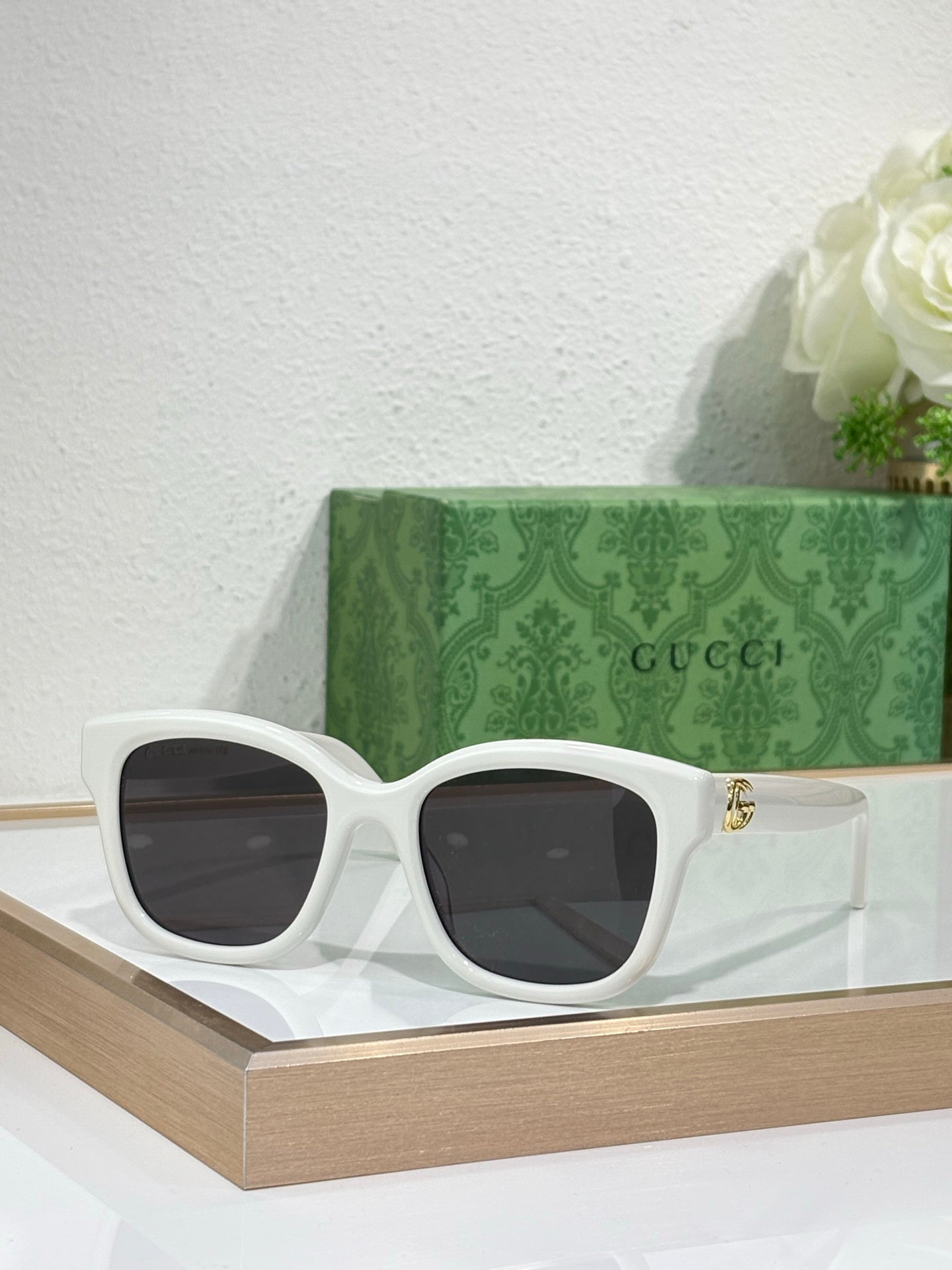 Gucci sunglasses with white frame and dark lenses, gold-toned temple accents.