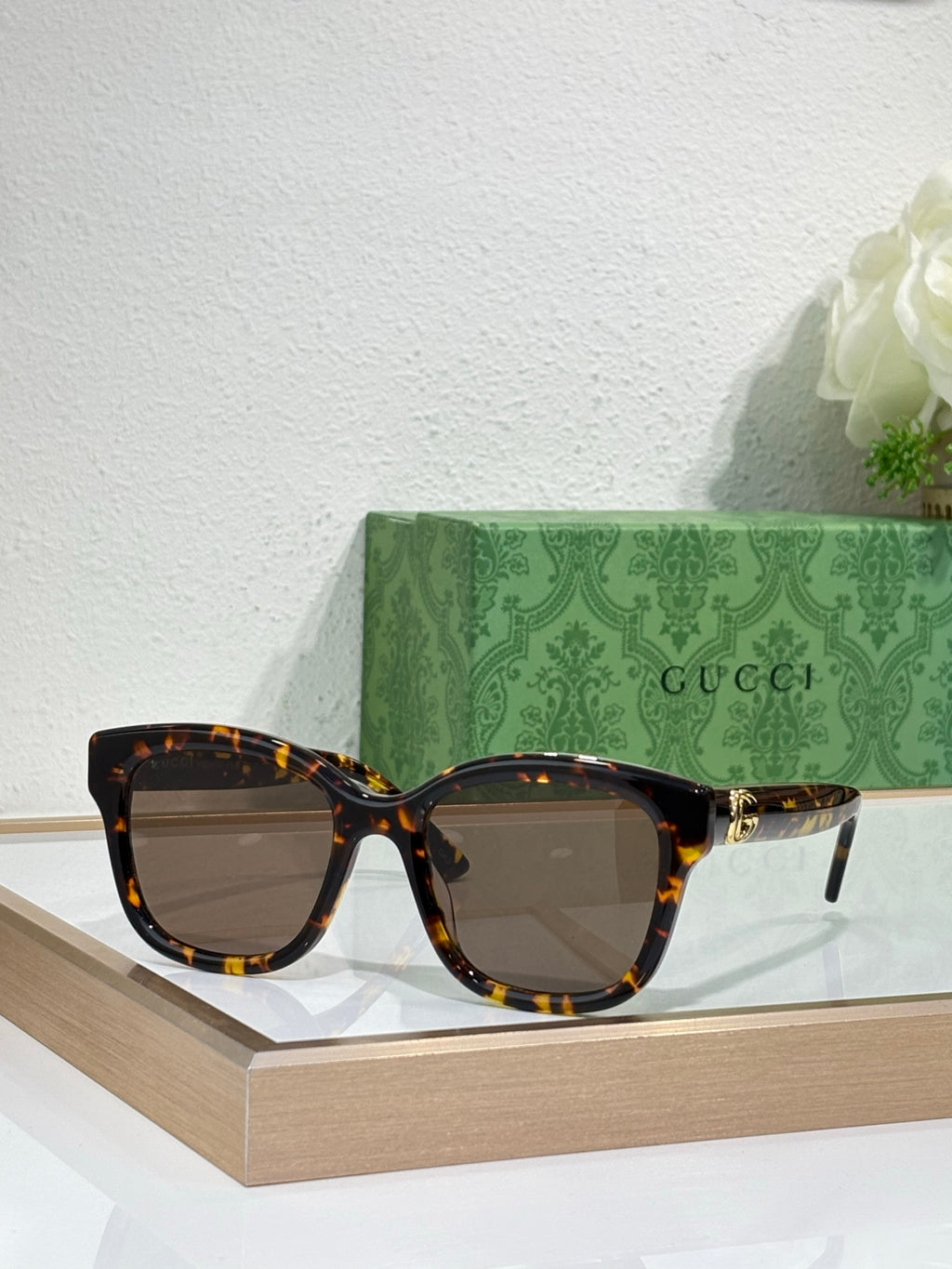 Gucci sunglasses with tortoiseshell frame and dark lenses, gold-toned temple accents.