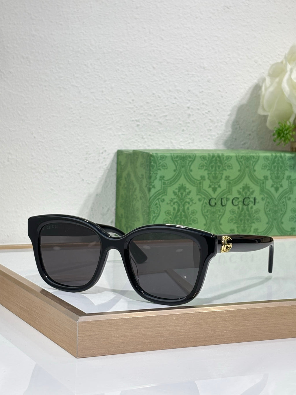 Gucci sunglasses with black frame and dark lenses, gold-toned temple accents.