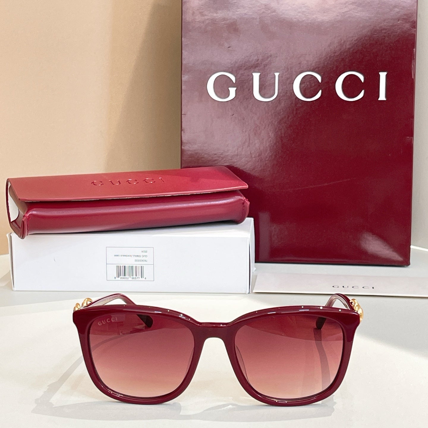 Gucci sunglasses with maroon frames and rose tinted lenses, gold logo temples