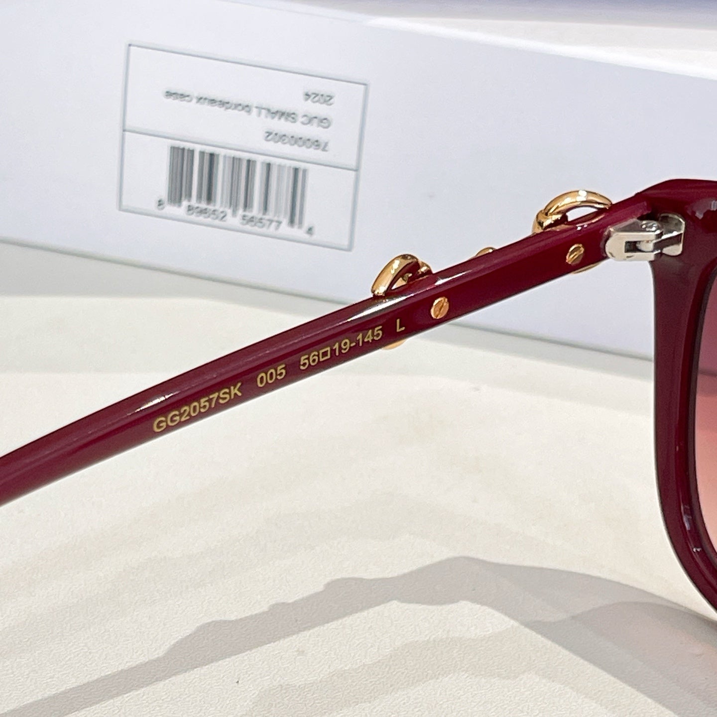 Gucci sunglasses side view with gold 'GU2057SK 005 560-19-145' marking on maroon temple