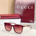 Gucci sunglasses front view with maroon frames, rose tinted lenses, and gold bridge