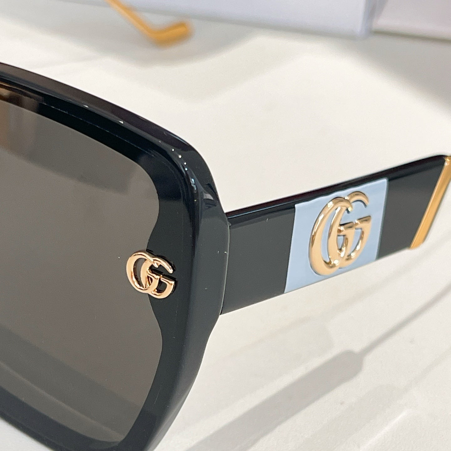 Black square sunglasses with gold double-G emblem on the temple