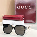 Black square sunglasses with dark lenses and gold logo accents