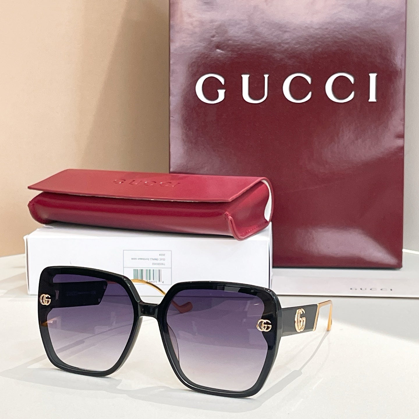 Black square sunglasses with purple-tinted lenses and gold logo accents