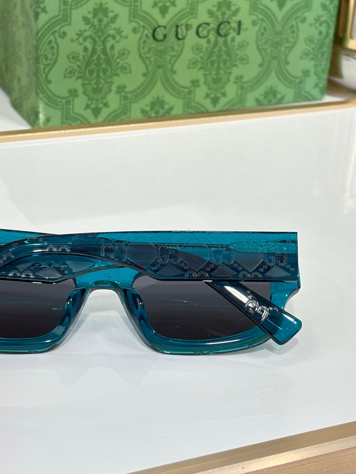 Gucci sunglasses with teal blue frames and dark rectangular lenses