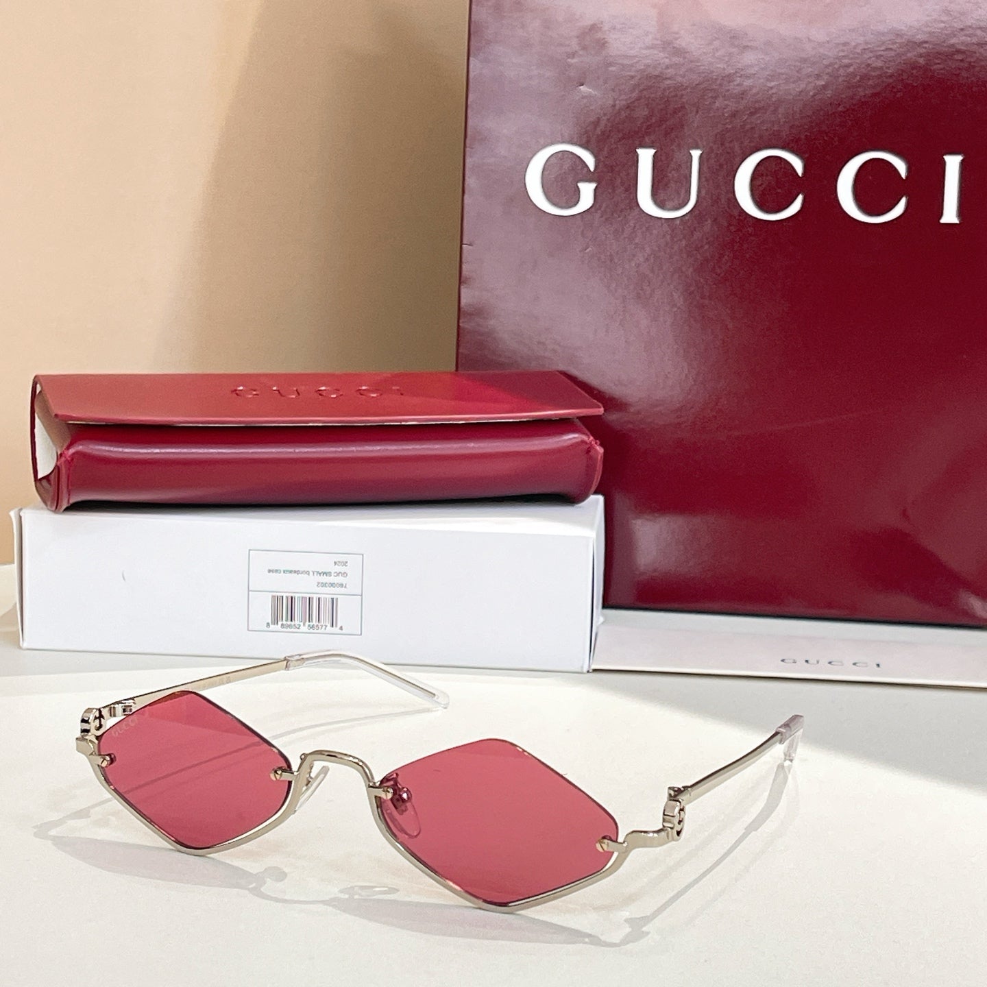 Gold-tone cat-eye sunglasses with red-pink lenses