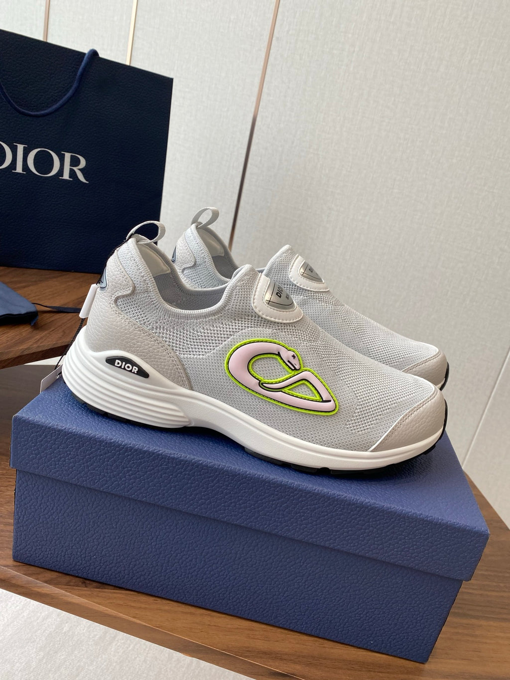 Unisex white slip-on sneakers on blue box, green logo accent on side