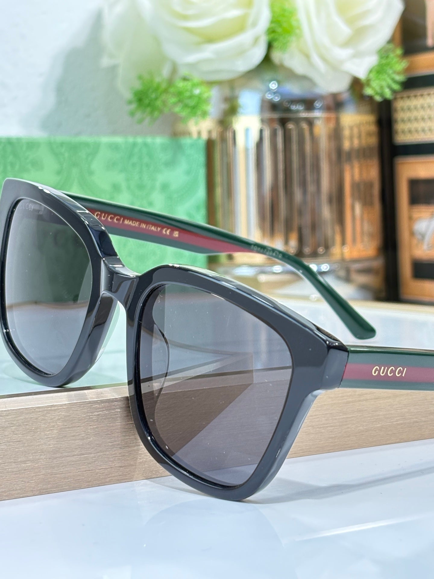 Sunglasses by Gucci with dark lenses and green temple details, angled side view.