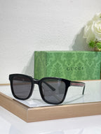 Sunglasses by Gucci with black oversized frames and dark tinted lenses, front view.