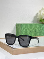 Sunglasses by Gucci with black oversized frames and dark tinted lenses, centered on display.