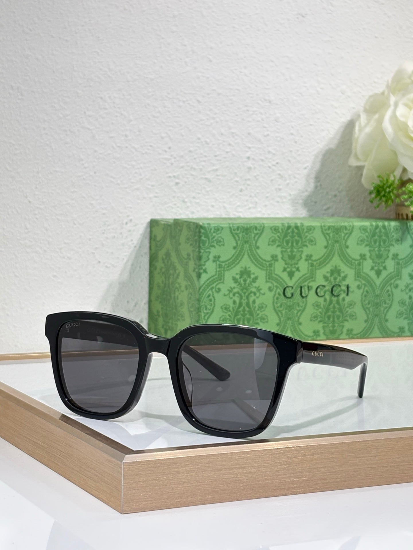 Sunglasses by Gucci with black oversized frames and dark tinted lenses, centered on display.