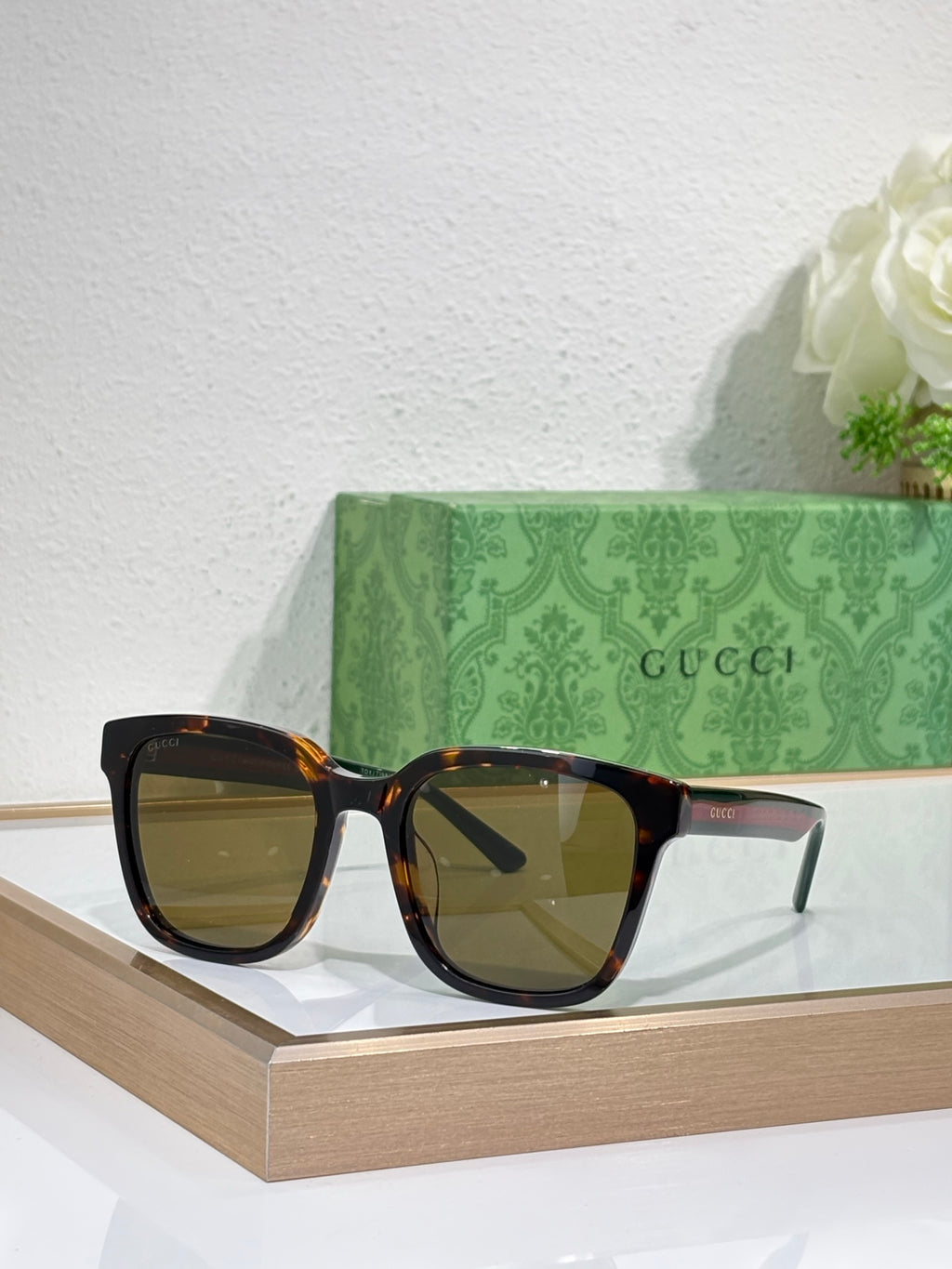 Sunglasses by Gucci with black oversized frames and amber-tinted lenses, front view.