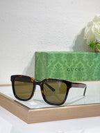 Sunglasses by Gucci with black oversized frames and amber-tinted lenses, front view.