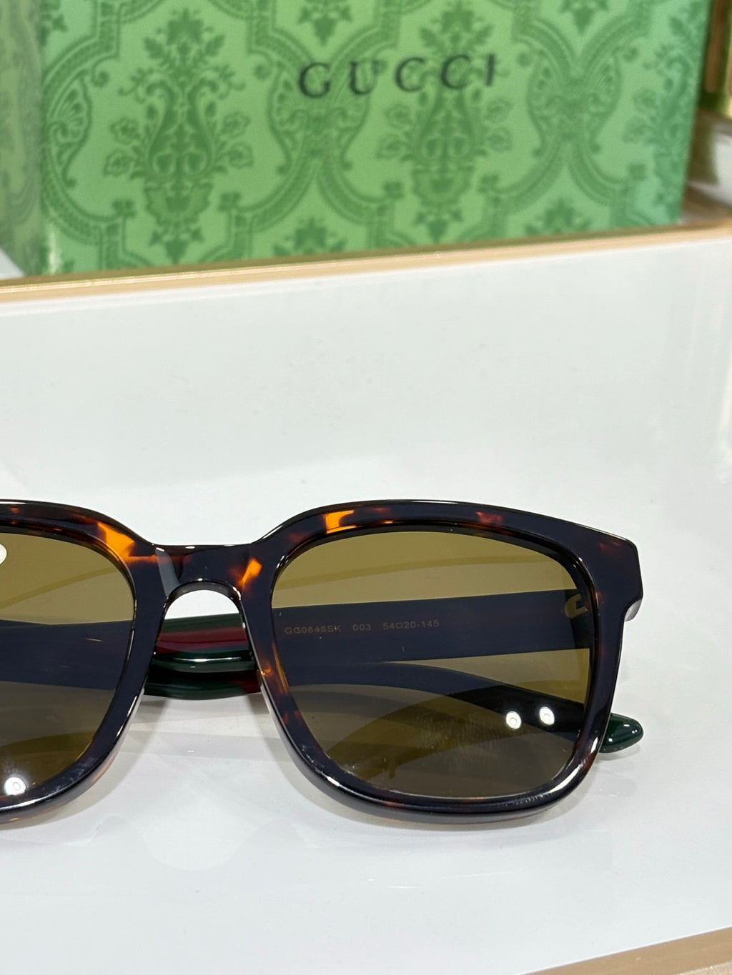 Sunglasses by Gucci close-up with tortoiseshell-effect frames and yellow-tinted lenses.
