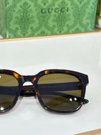 Sunglasses by Gucci close-up with tortoiseshell-effect frames and yellow-tinted lenses.
