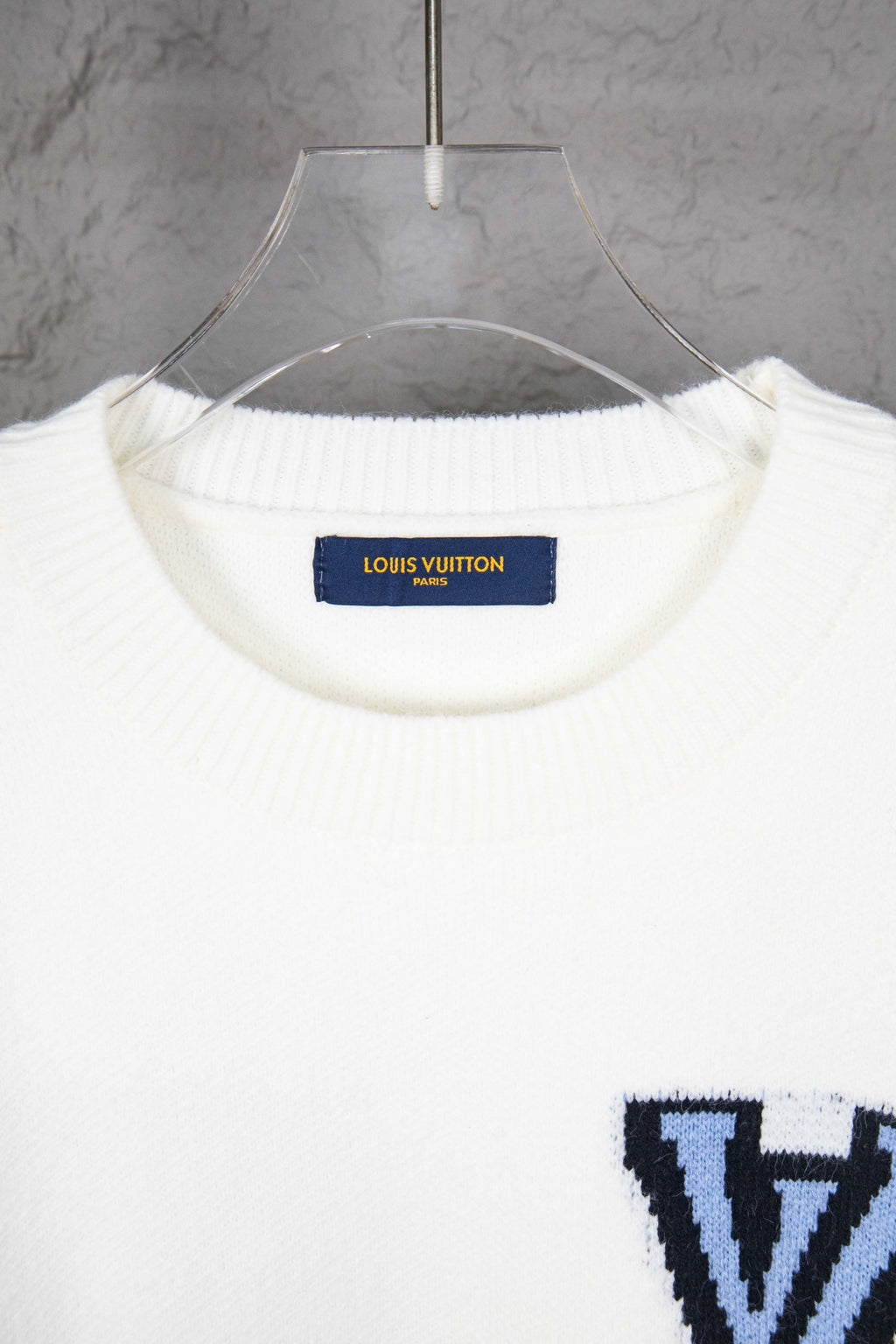 White knit sweater neckline with blue Louis Vuitton label inside collar
