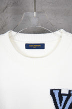 White knit sweater neckline with blue Louis Vuitton label inside collar