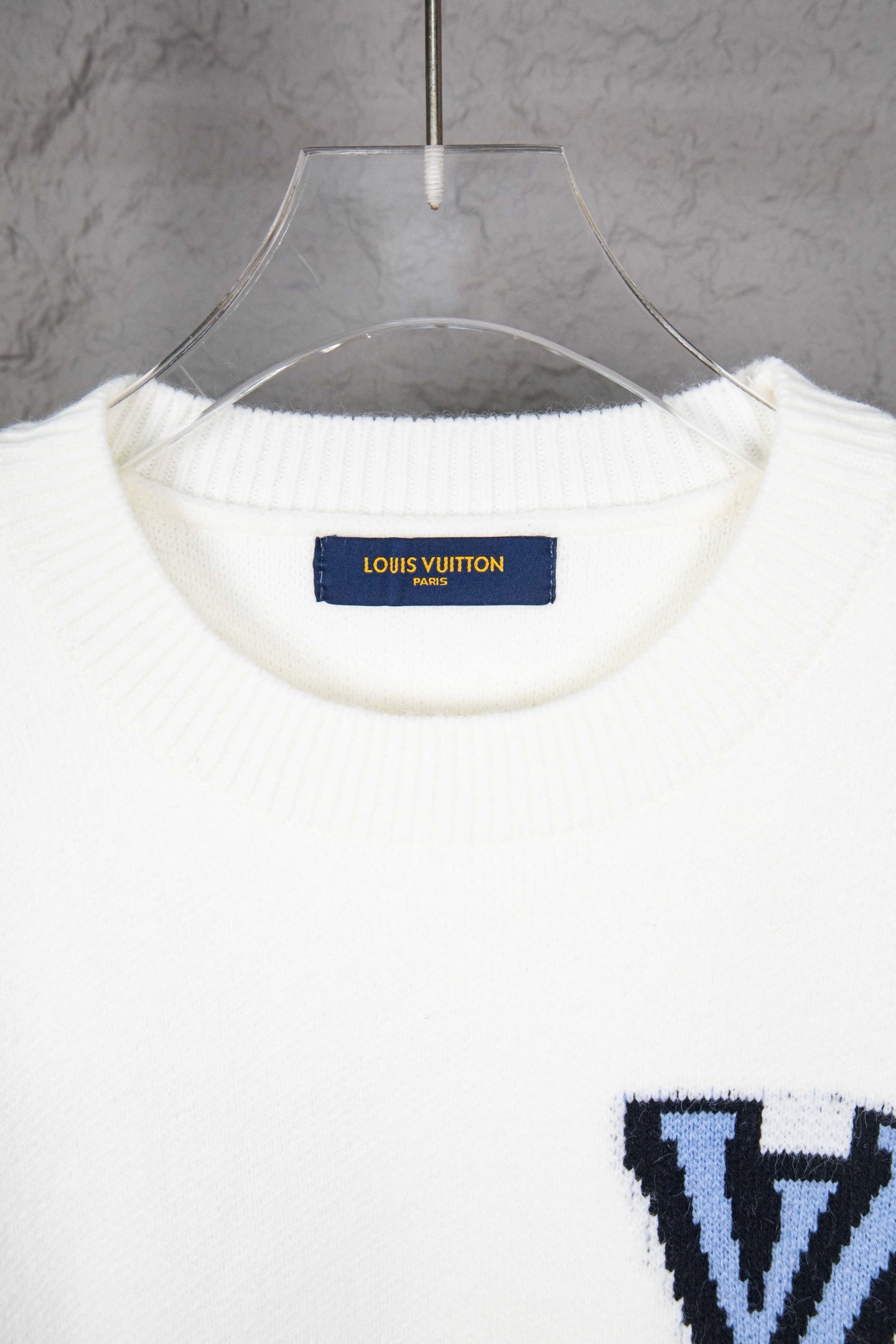 White knit sweater neckline with blue Louis Vuitton label inside collar