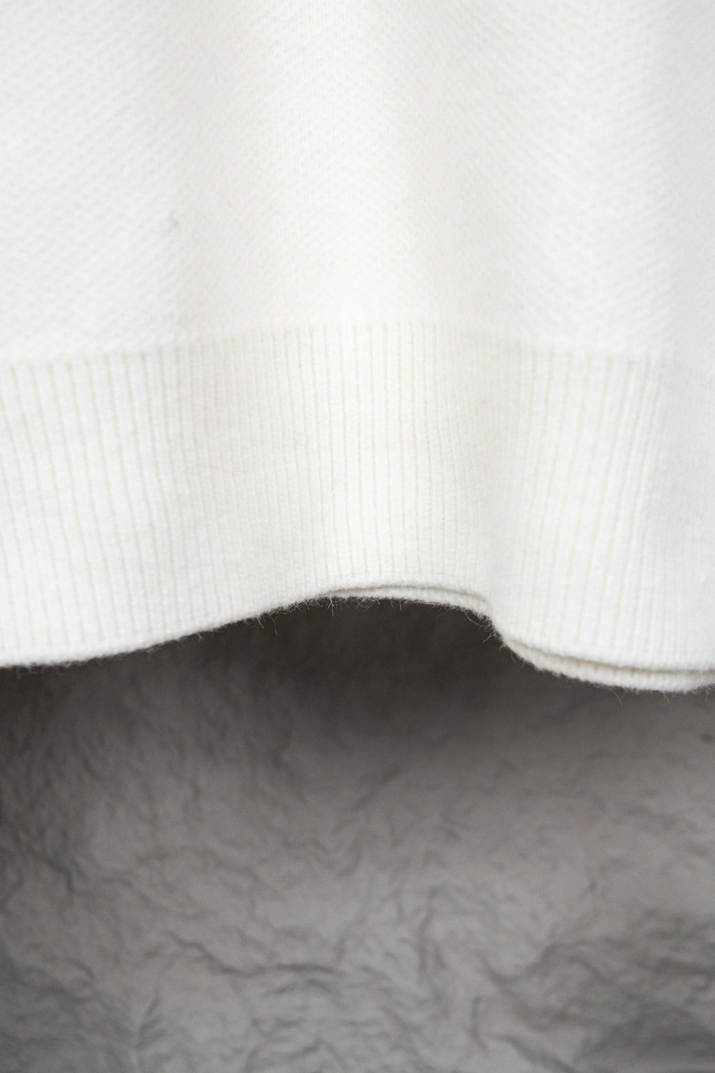 White ribbed knit hem with curved edge on sweater