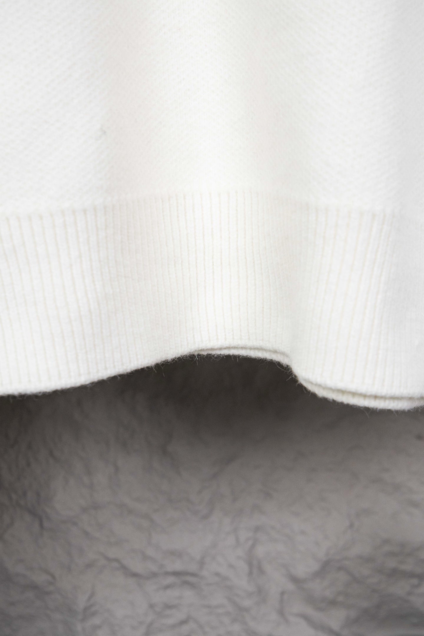 White ribbed knit hem with curved edge on sweater