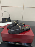 Gucci black horsebit mule with gold hardware and embossed pattern on the upper