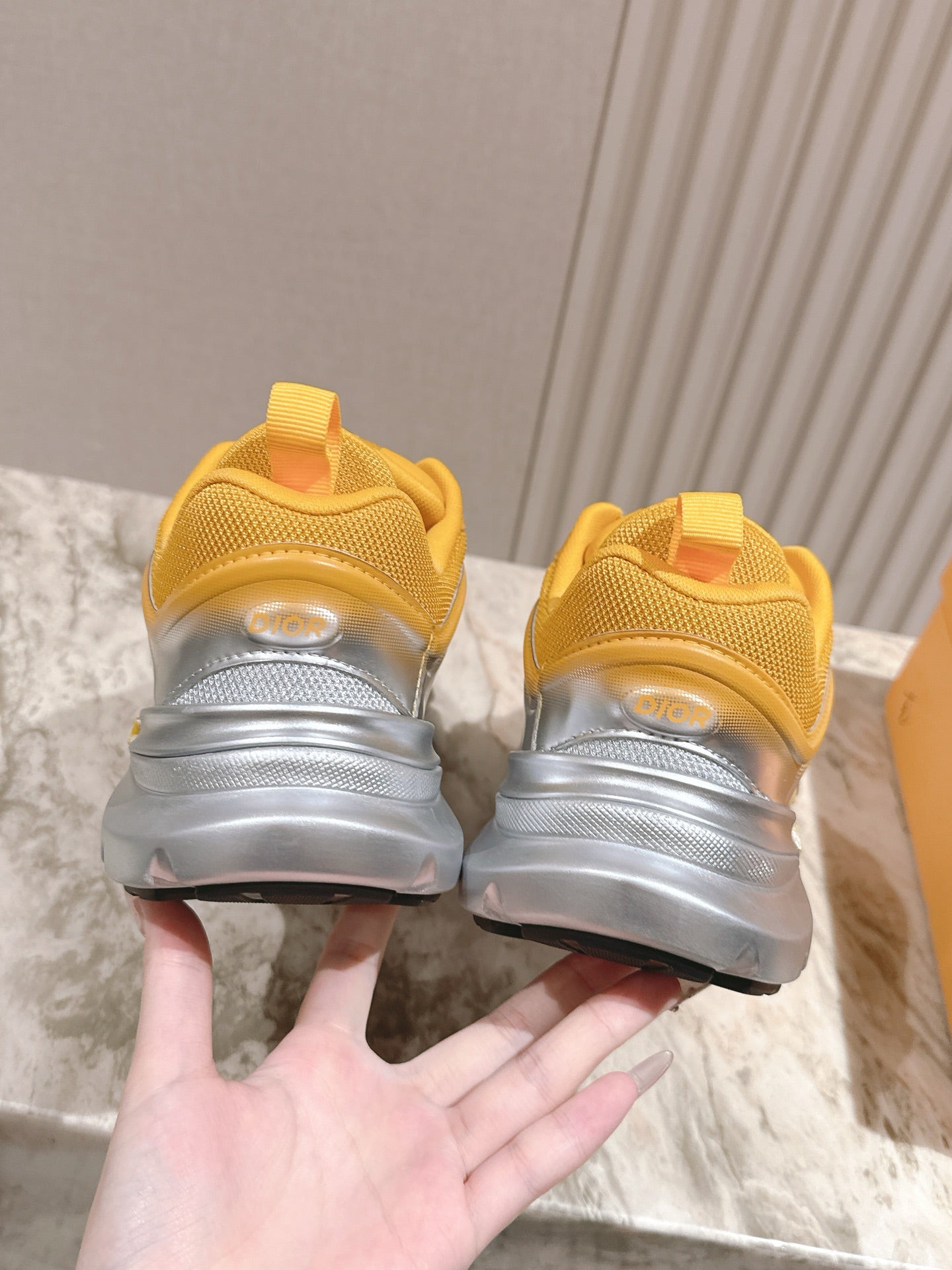 Dior unisex sneakers heel view, yellow uppers with thick gray and silver soles