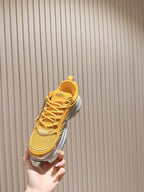 Dior unisex sneaker held up, yellow lace-up upper with silver midsole detail