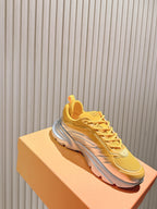 Dior unisex sneakers on box, yellow upper with gray sole and side logo detail