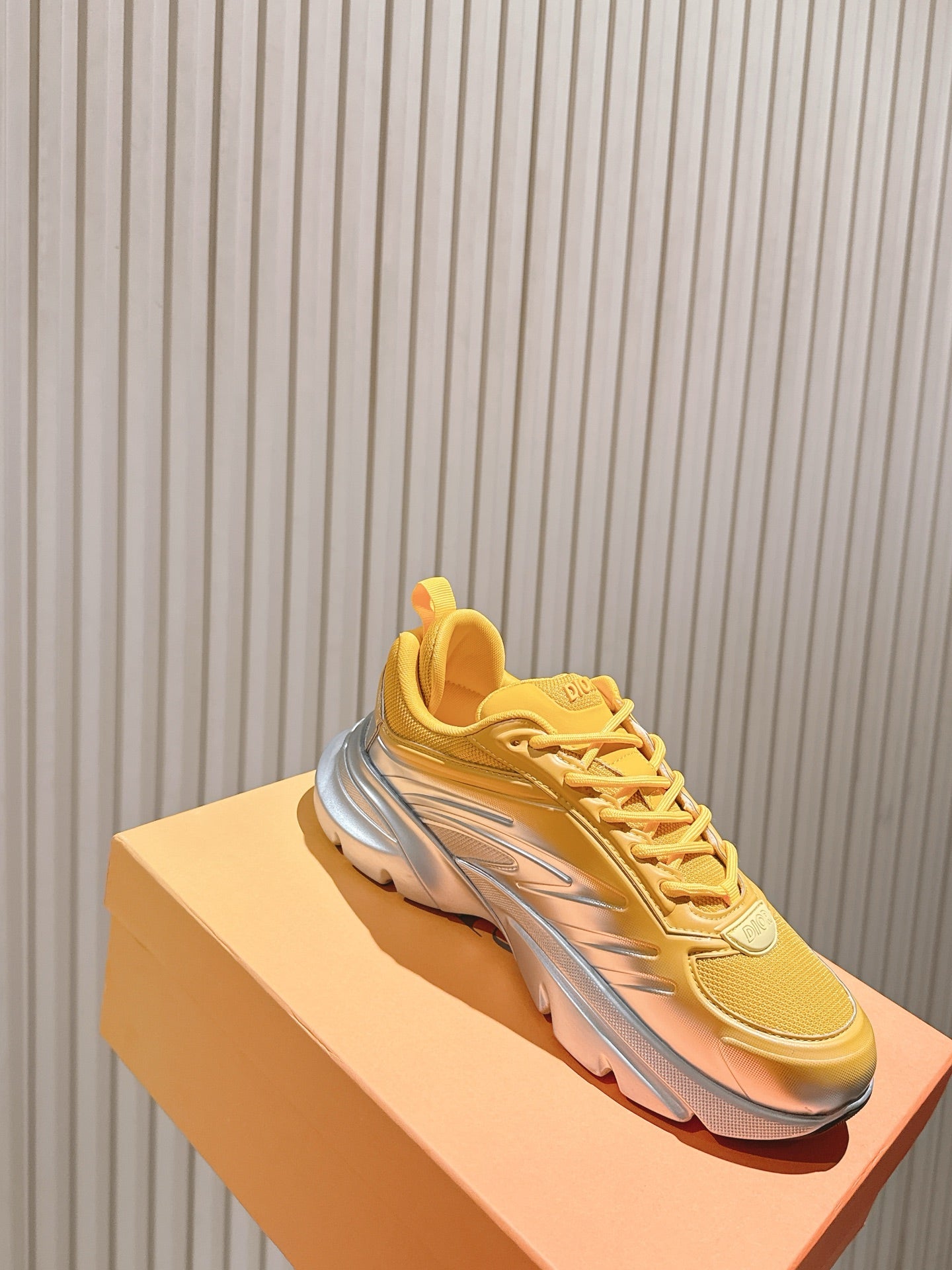 Dior unisex sneakers on box, yellow upper with gray sole and side logo detail