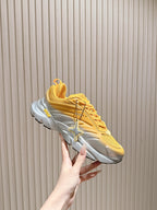 Dior unisex sneakers side view, yellow upper with sculpted gray sole and “Dior” mark