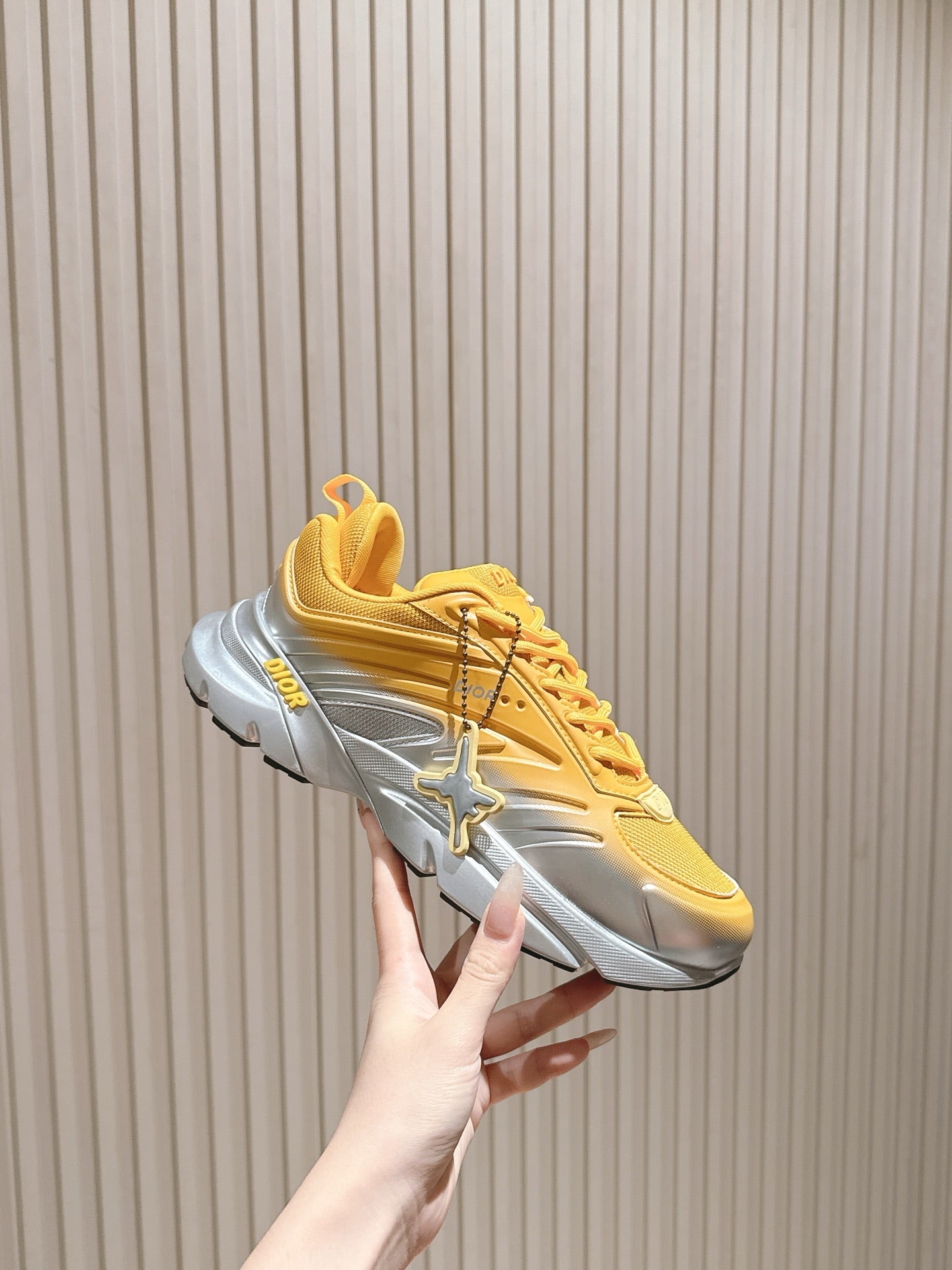 Dior unisex sneakers side view, yellow upper with sculpted gray sole and “Dior” mark
